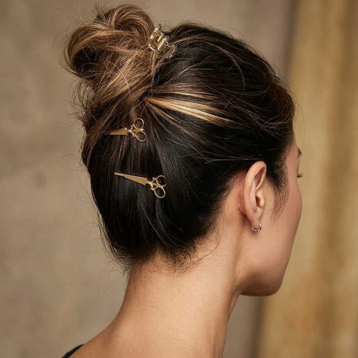 Woman with styled hair featuring gold hair accessories against a neutral background