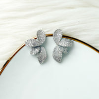 Silver leaf-shaped earrings on a white plate with a white background. Seraphine Earrings - The Songbird Collection - pave - floral petal