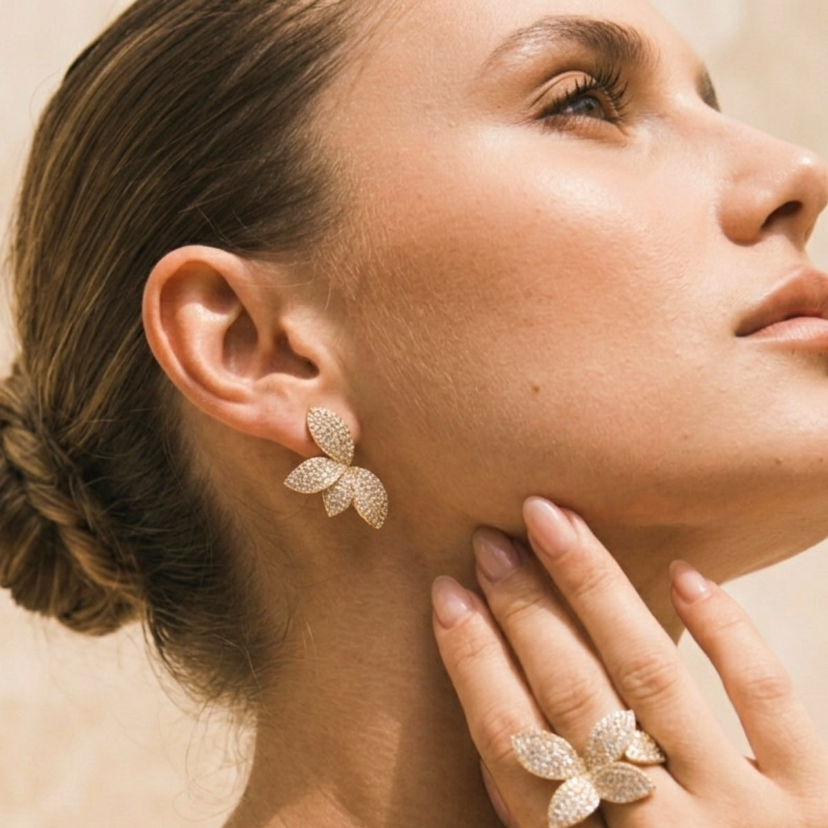 Close-up of a woman wearing gold butterfly earrings and a matching ring.