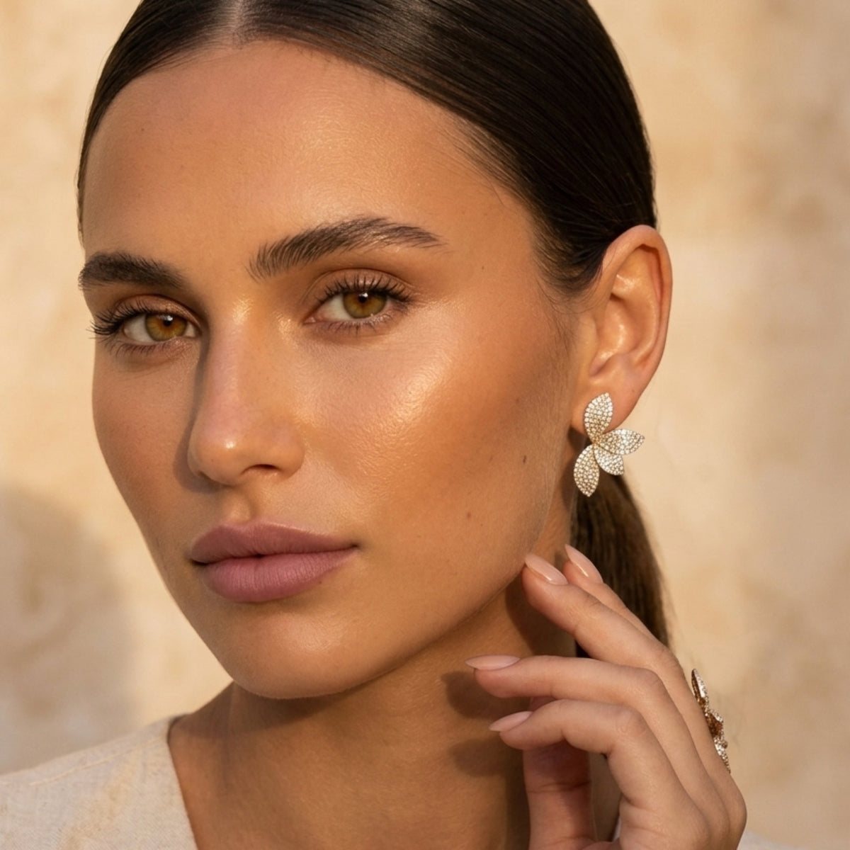 Close-up of a woman wearing butterfly earrings with a neutral background