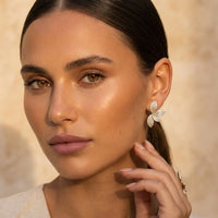 Close-up of a woman wearing butterfly earrings with a neutral background