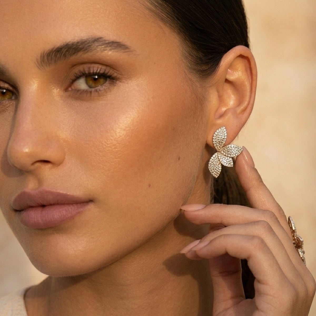 Close-up of a woman wearing a sparkling butterfly earring against a neutral background