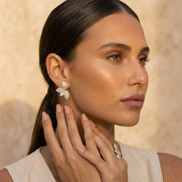 Woman wearing butterfly earrings with a neutral background. Seraphine Earrings - The Songbird Collection - pave - floral petal