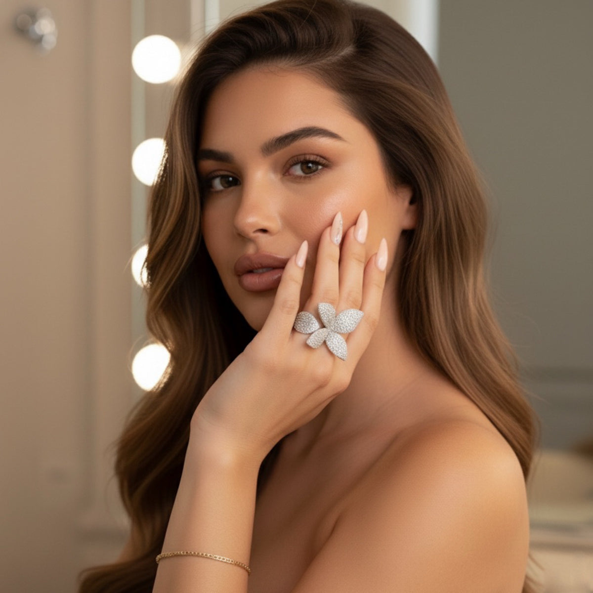 Woman wearing a silver wrap around ring with a floral design in front of a mirror with lights.