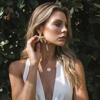 Woman wearing starfish earrings outdoors with greenery in the background  Starfish_Statement_Earrings_-_The_Songbird_Collection_