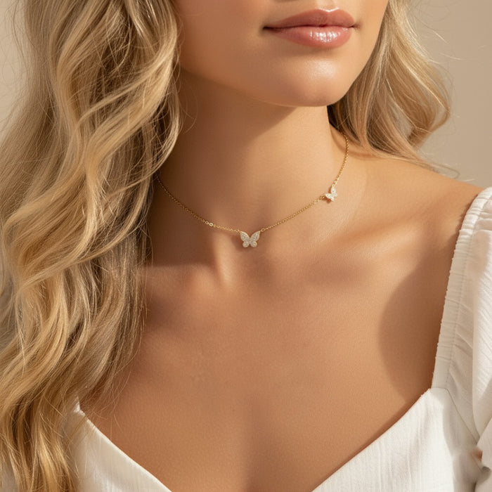 Close-up of a woman wearing a delicate butterfly necklace against a neutral background