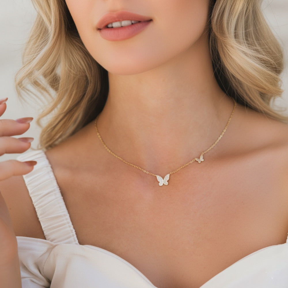 Woman wearing a delicate gold necklace with butterfly pendants on a plain background