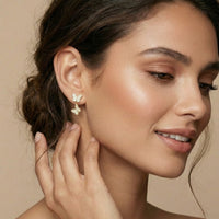 Woman wearing butterfly earrings with a neutral background