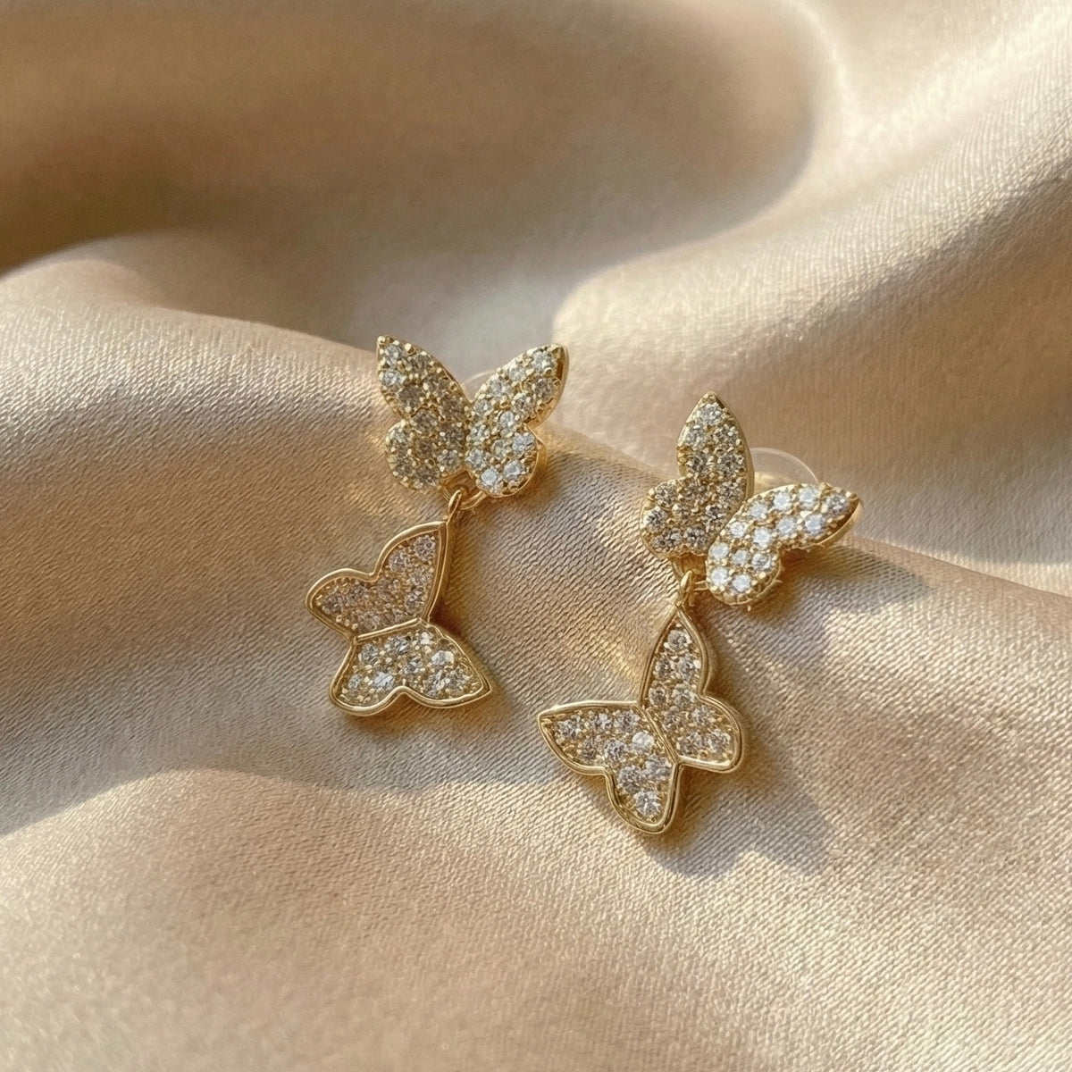 Butterfly-shaped earrings with gemstones on a beige fabric   Sweet Butterfly Earrings - The Songbird Collectionbackground