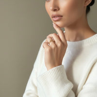 Woman wearing 2 gold rings and a white sweater with a neutral background. Tessa Ring Set - The Songbird Collection - stainless s