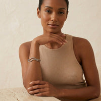 Woman wearing a beige sleeveless top against a neutral background. The_Contour_Cuff_Bracelet_-_The_Songbird_Collection_