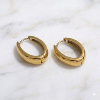 Gold hoop earrings on a marble surface