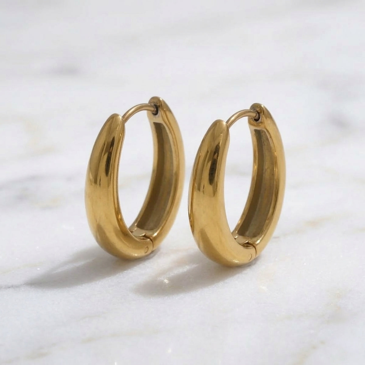 Gold hoop earrings on a marble surface