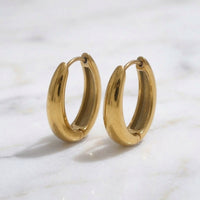 Gold hoop earrings on a marble surface