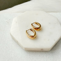 Gold oblong teardrop hoop earrings on a marble surface - The Ever Teardrop Hoop Earrings - The Songbird Collection