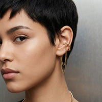 Close-up of a woman wearing gold hoop earrings against a neutral  - The Flow Ear Cuff - The Songbird Collection
