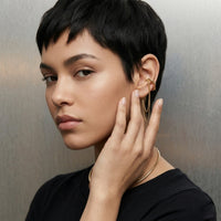 Woman wearing gold hoop earrings with a neutral background. The Flow Ear Cuff - The Songbird Collection