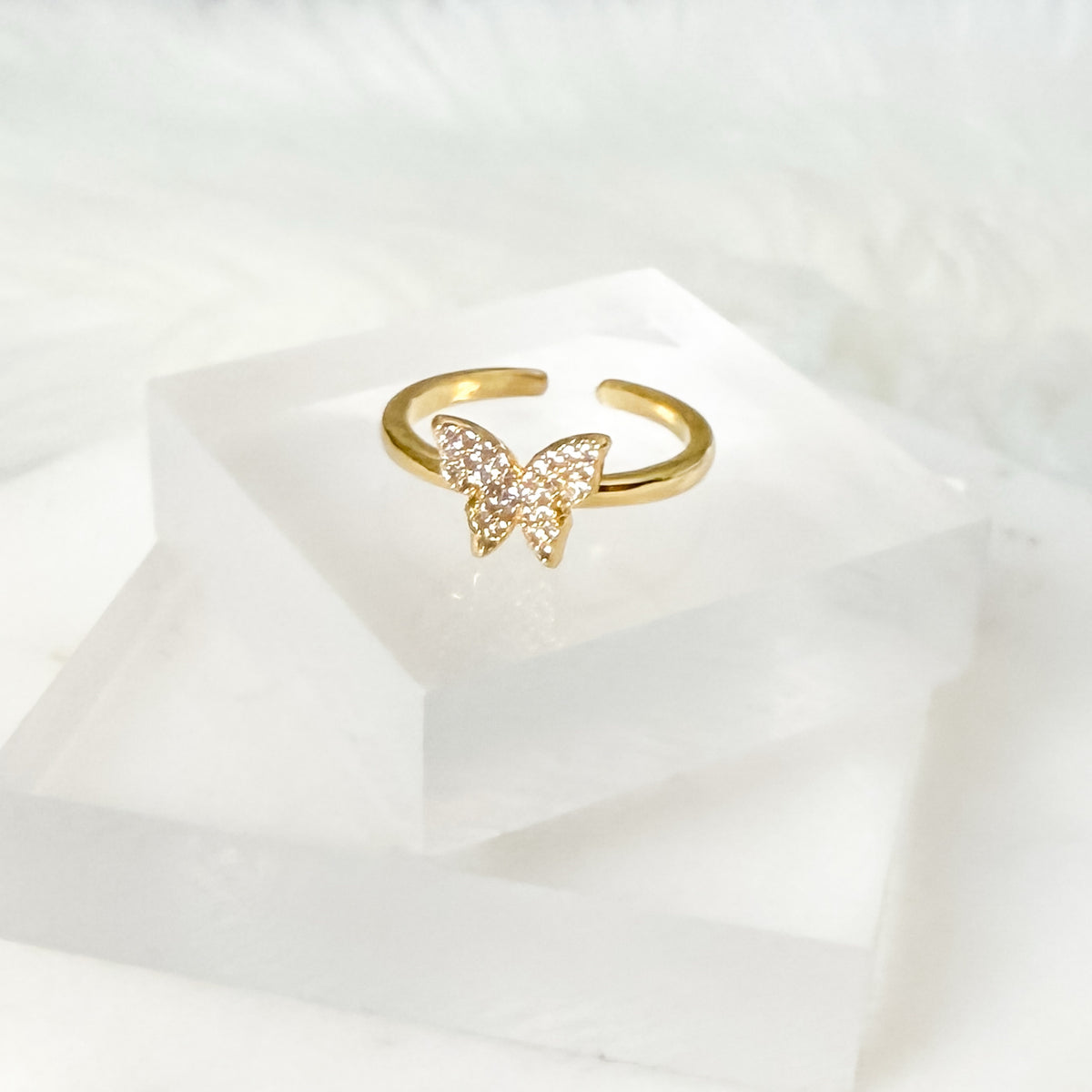 Gold butterfly ring on a white fabric background
