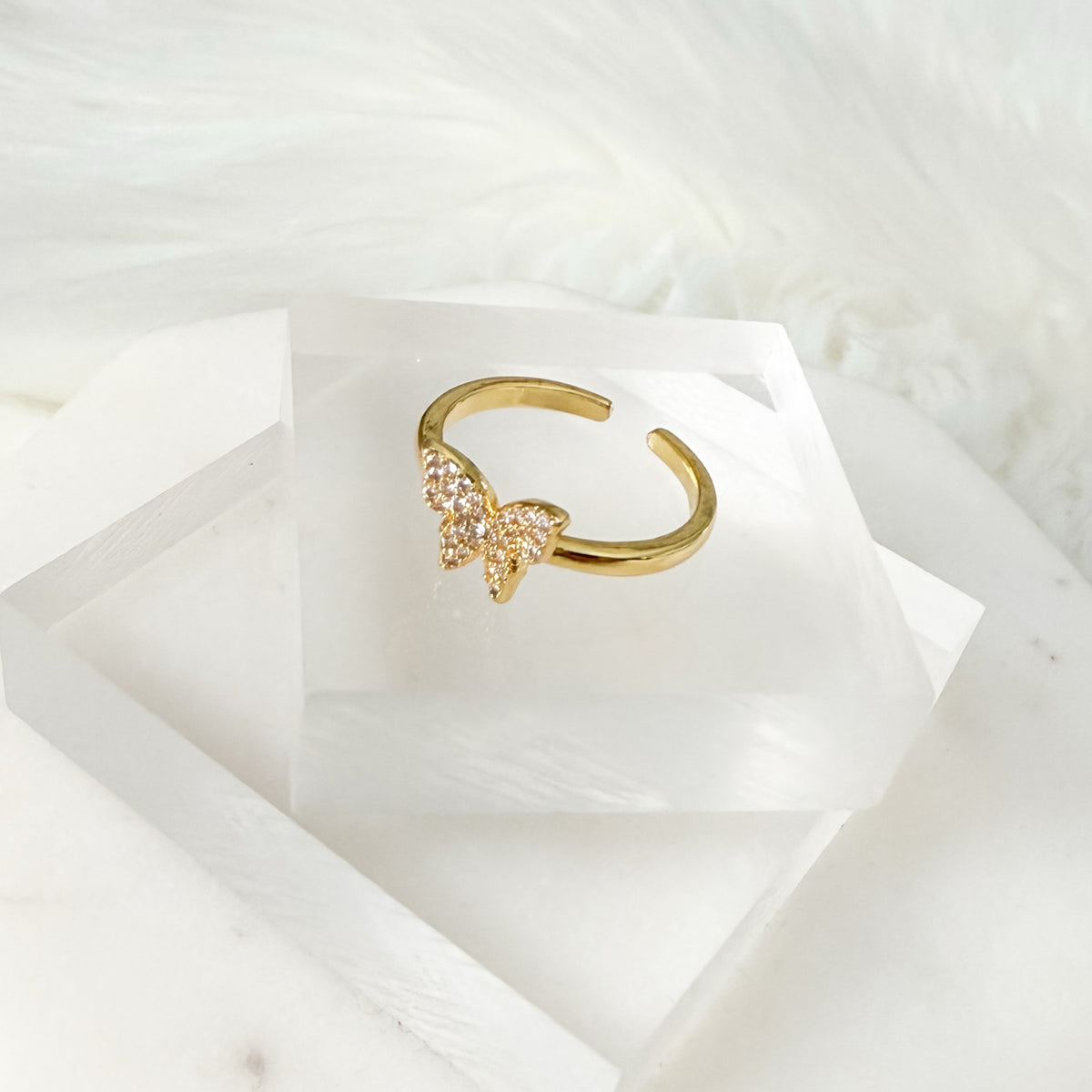 Gold ring with a butterfly design on a white marble surface