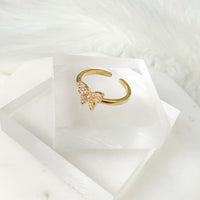 Gold ring with a butterfly design on a white marble surface