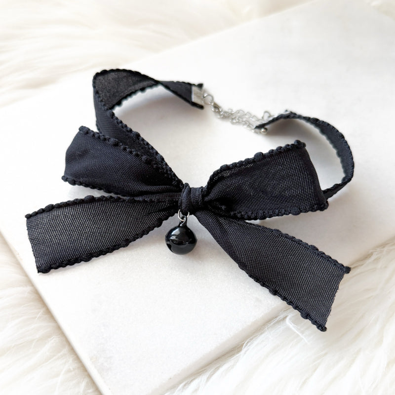 Black bow choker necklace on a white surface