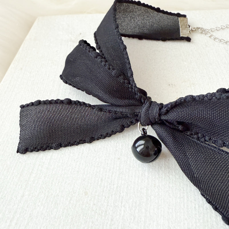 Black bow necklace with a pendant on a light background
