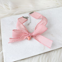 Pink ribbon lace choker on a white card with a soft background