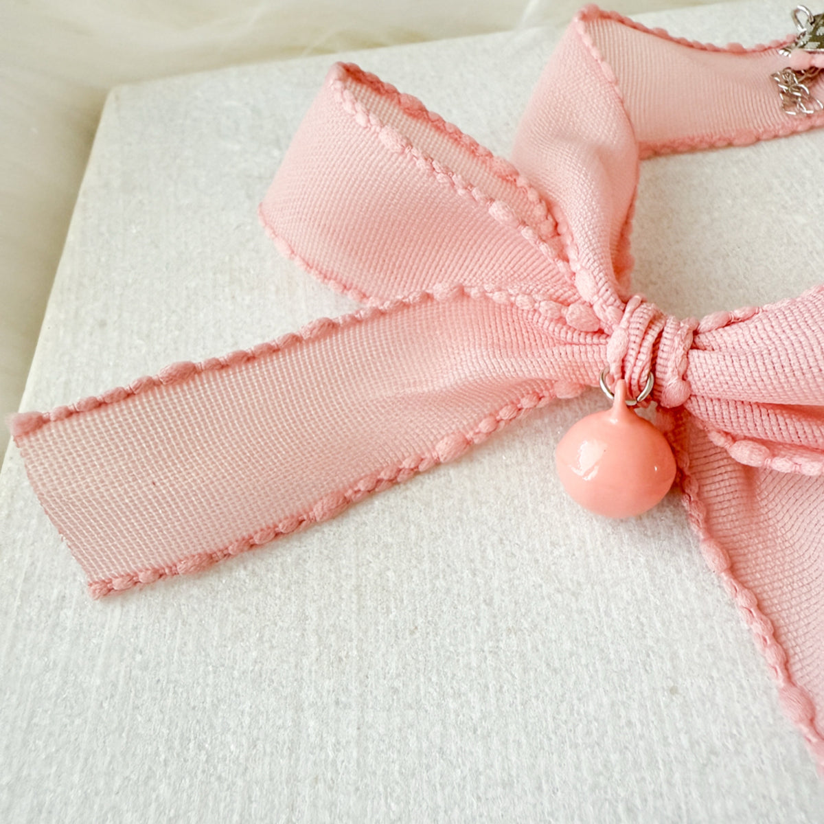 Close-up of a pink bow with a decorative charm on a white background