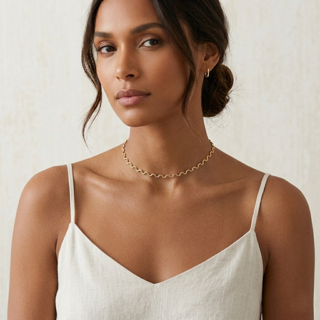 Woman wearing a gold necklace against a neutral background