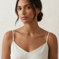 Woman wearing a gold necklace against a neutral background