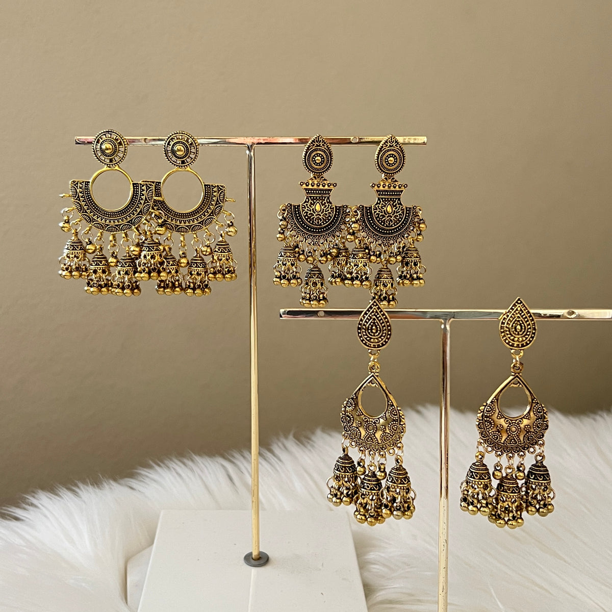 A collection of vintage metal earrings displayed on a stand, featuring bohemian style with ethnic and exotic patterns.